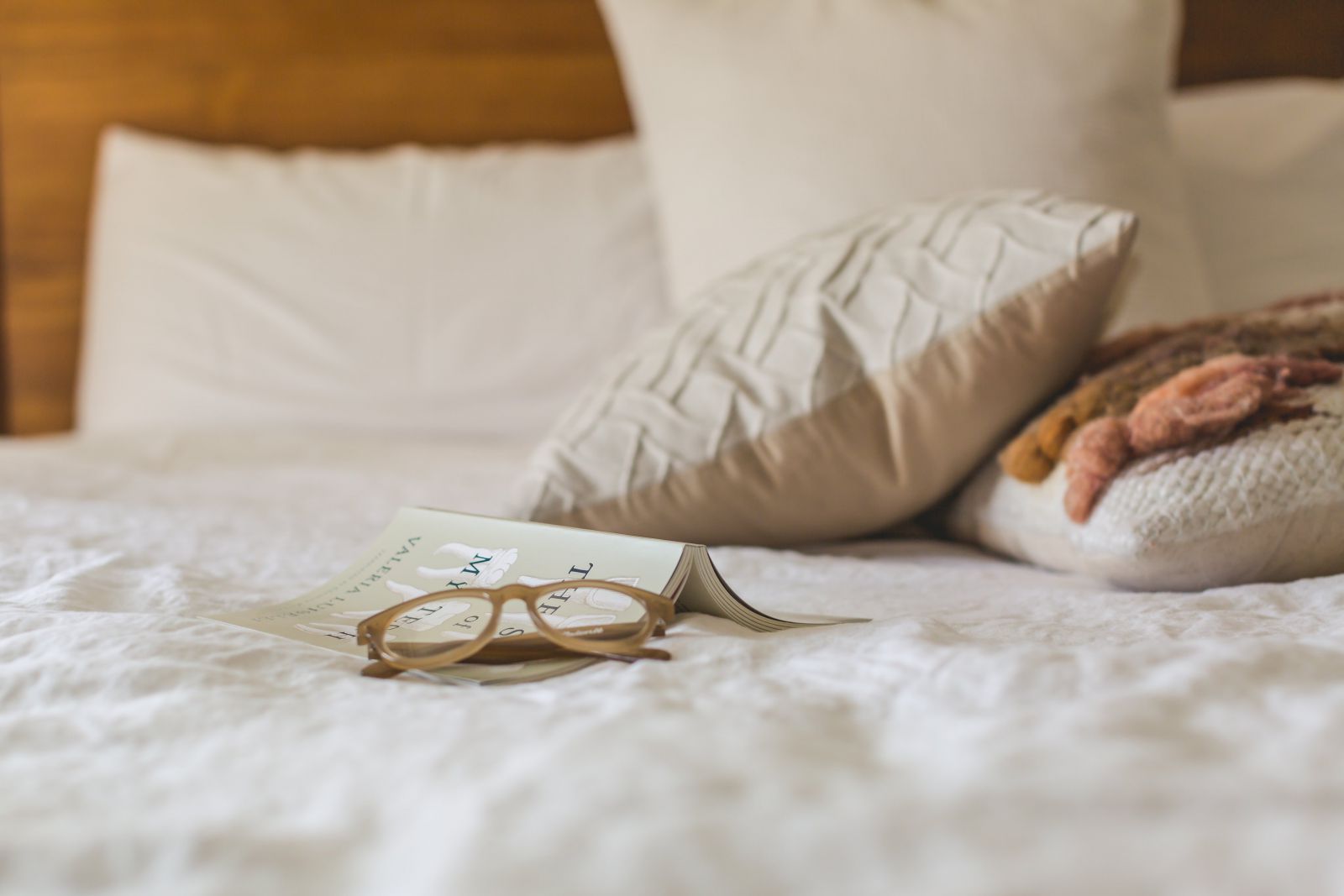 Cama com livro aberto e almofadas