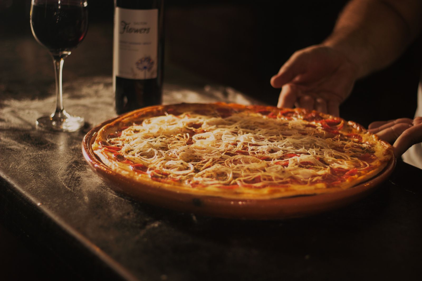 Pizza ao lado de uma taça de vinho