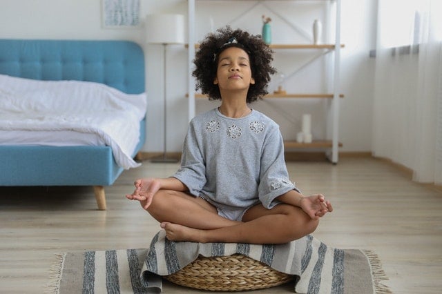 Menina negra sentada numa cesta meditando.