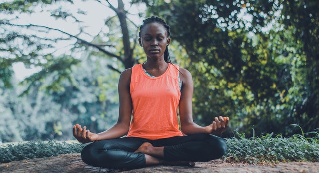 Mulher negra meditando ao ar livre.