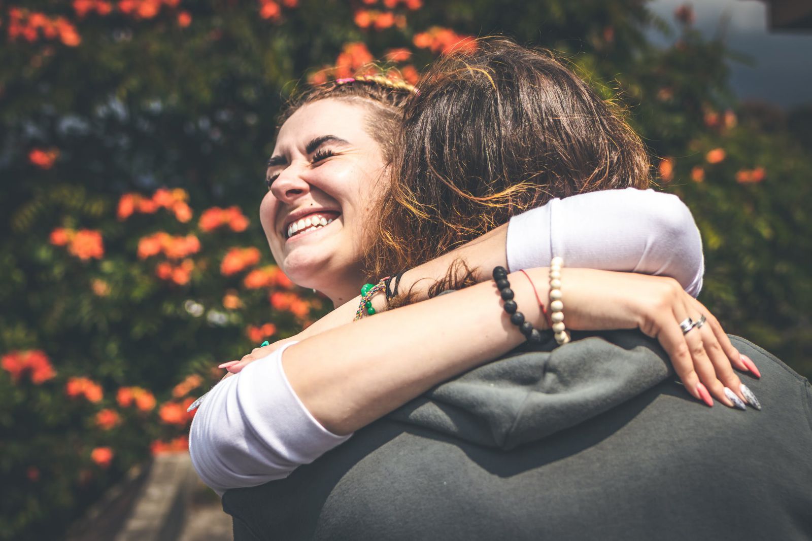 Duas mulheres se abraçando ao lado de uma árvore com flores