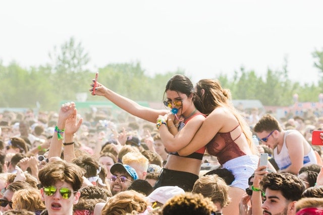 Mulheres brancas abraçadas num festival.