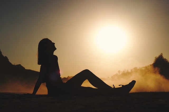 Silhueta de mulher sorrindo no pôr do sol.