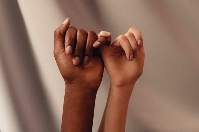 Mãos negra e branca entrelaçadas.